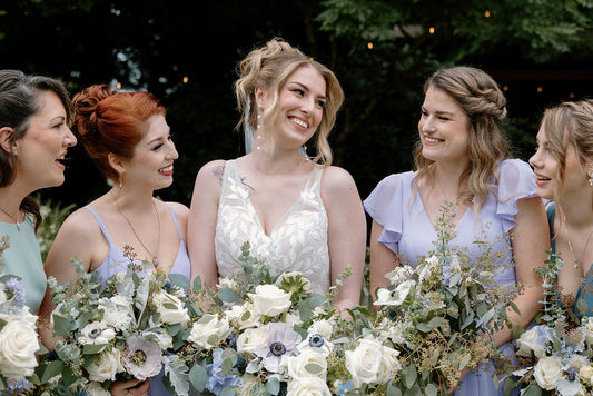 A wedding bouquet featuring an elegant combination of whites, pale purples, and dusty blue flowers. 